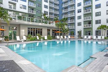 A large swimming pool in front of a building with a balcony.